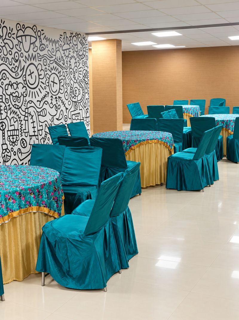 The indoor hall with round tables and teal chairs